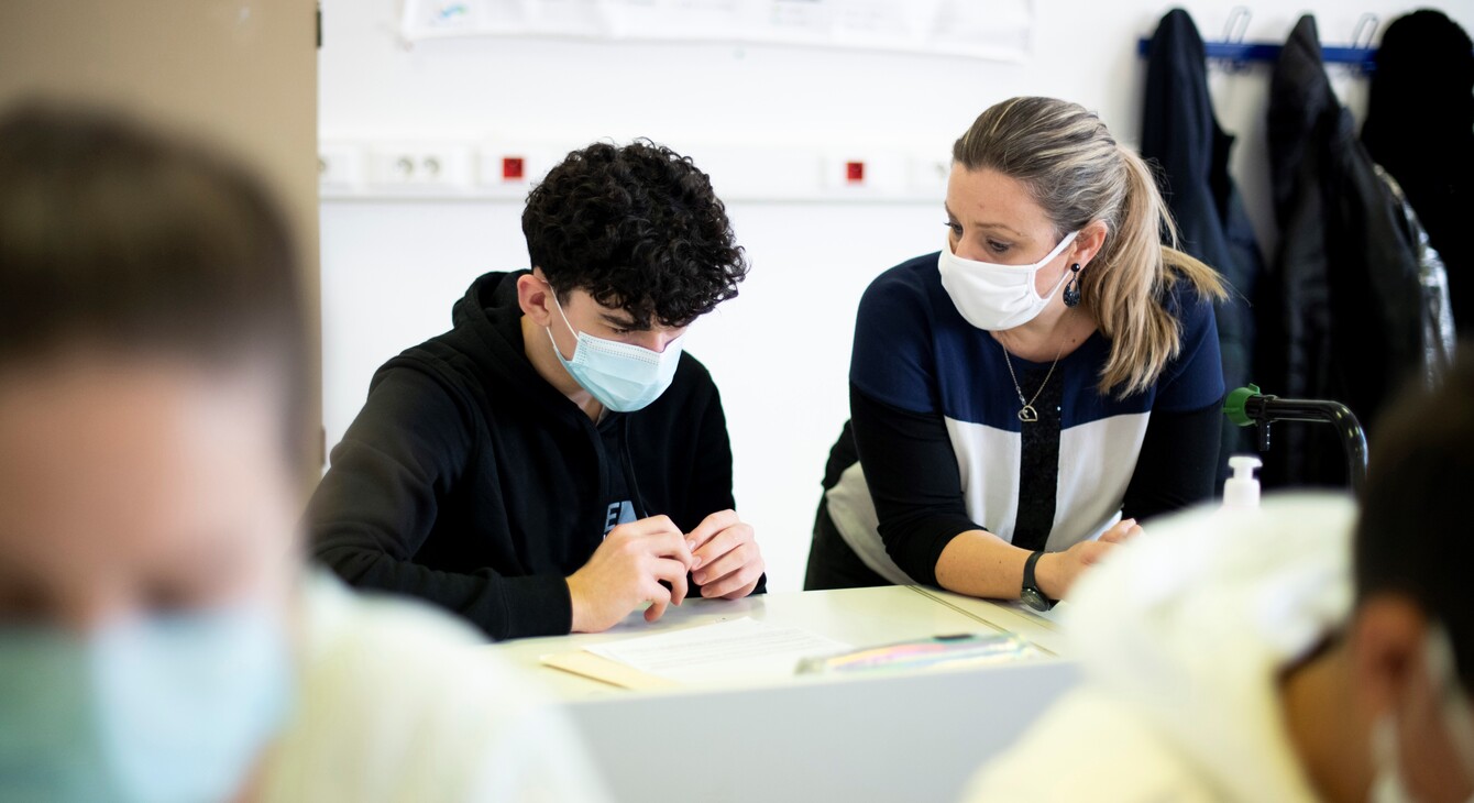 Une enseignante aux côtés d'un élève