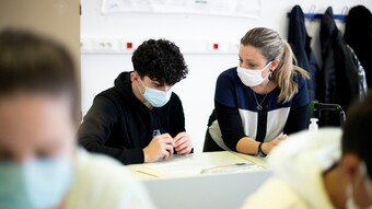 Une enseignante aux côtés d'un élève